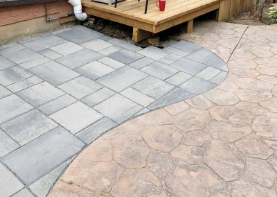 A residential backyard with an interlocking stone patio